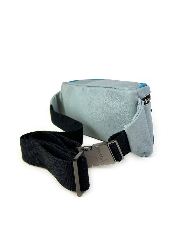 Light blue leather sling bag with a detachable black strap and metal buckle