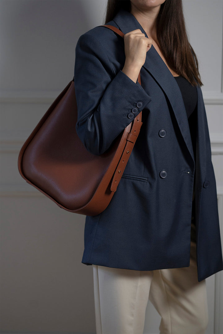 Woman in a dark blazer carrying a large brown leather handbag