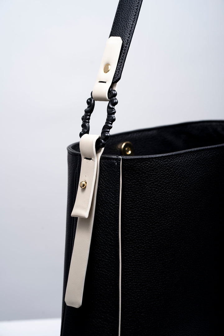 Black leather handbag with white strap detail and gold hardware