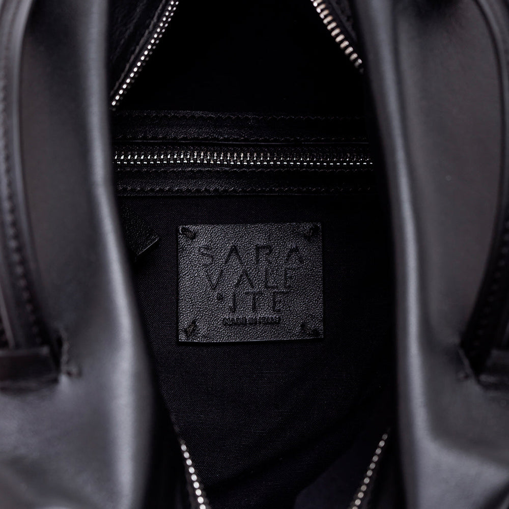 Inside view of a black leather handbag showing the brand label and zipper pocket
