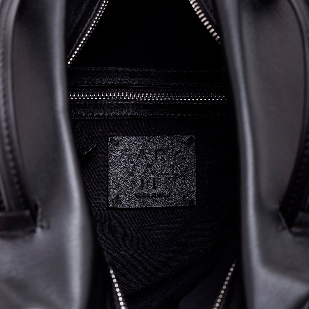 Inside view of a black leather handbag showing the brand label and zipper pocket