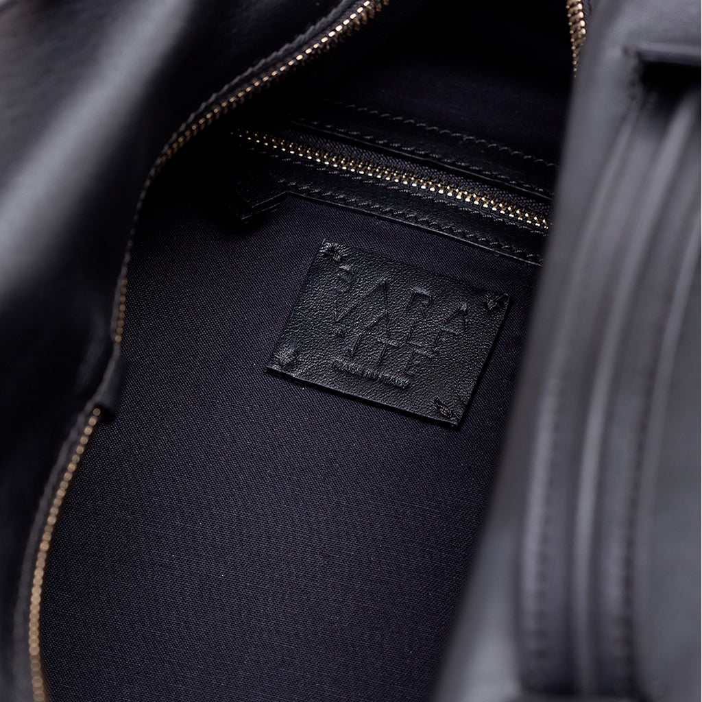 Close-up of black leather jacket interior showing stitching and label