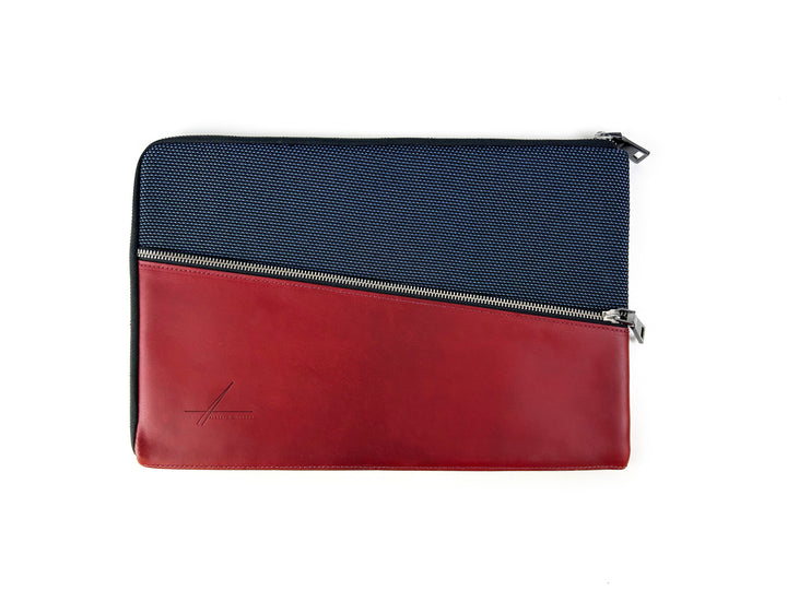 Elegant laptop sleeve with navy blue fabric and red leather, diagonal zipper closure