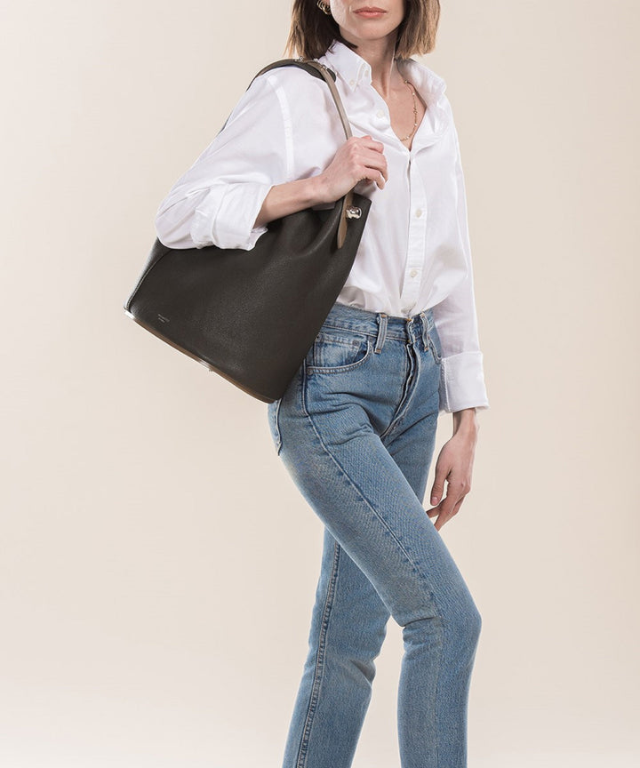 Woman wearing white shirt and blue jeans holding black leather handbag