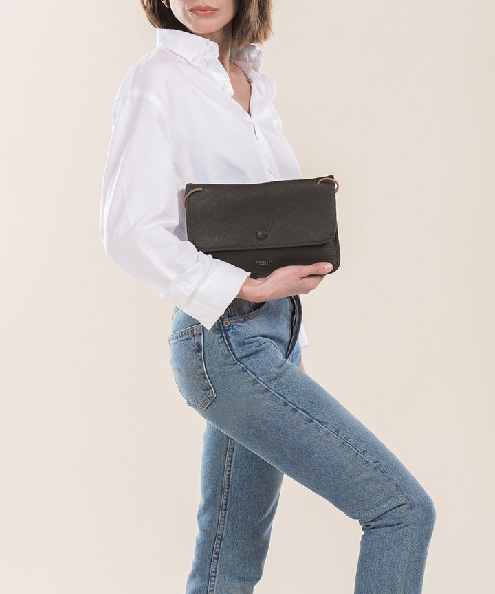 Woman in white shirt and jeans holding a black leather clutch