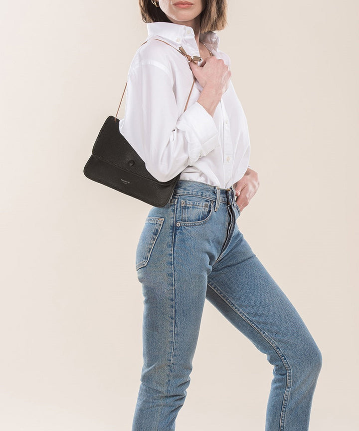 Woman wearing a white shirt with blue jeans and carrying a stylish black shoulder bag