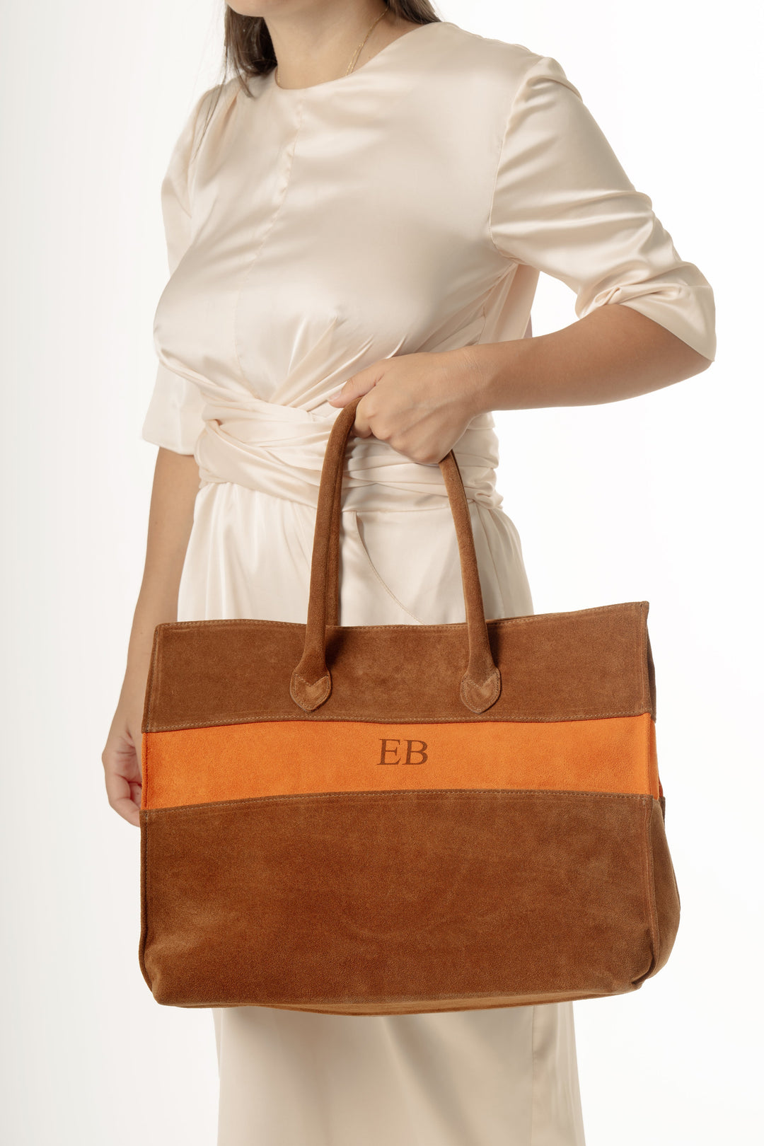 Woman holding a large brown and orange tote bag with initials EB on it