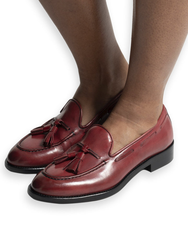 Red leather tassel loafers on feet