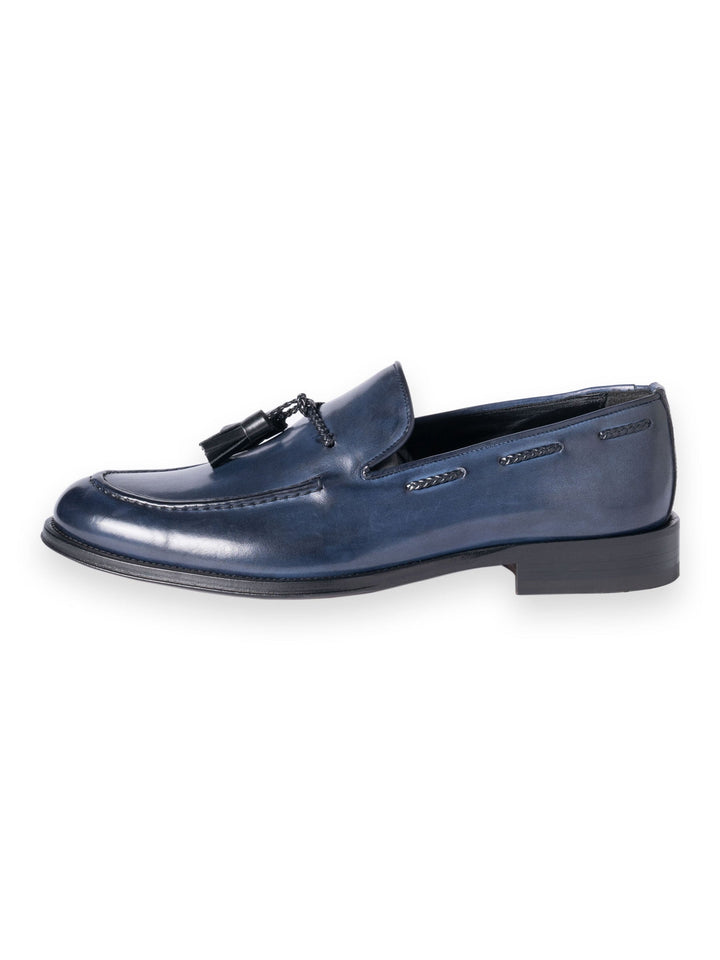 Blue leather loafers with tassel and stitching details on white background