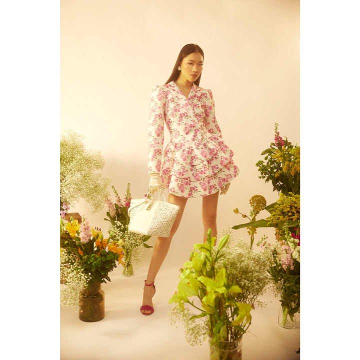 Woman in a floral dress posing among lush flowers and greenery