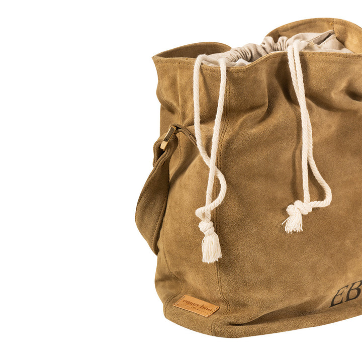 Tan suede drawstring handbag with white corded straps