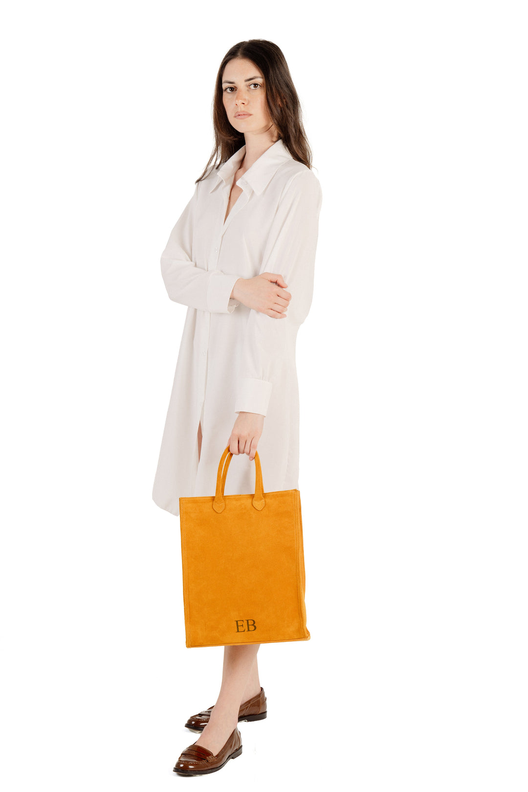 Woman in white dress holding orange tote bag against white background