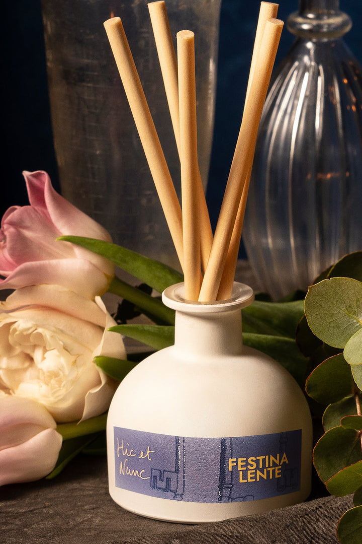 Ceramic diffuser with reed sticks and flowers on dark background