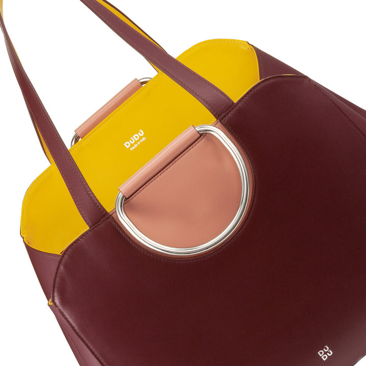 Colorful designer handbag with yellow, maroon, and pink sections featuring a circular metal handle