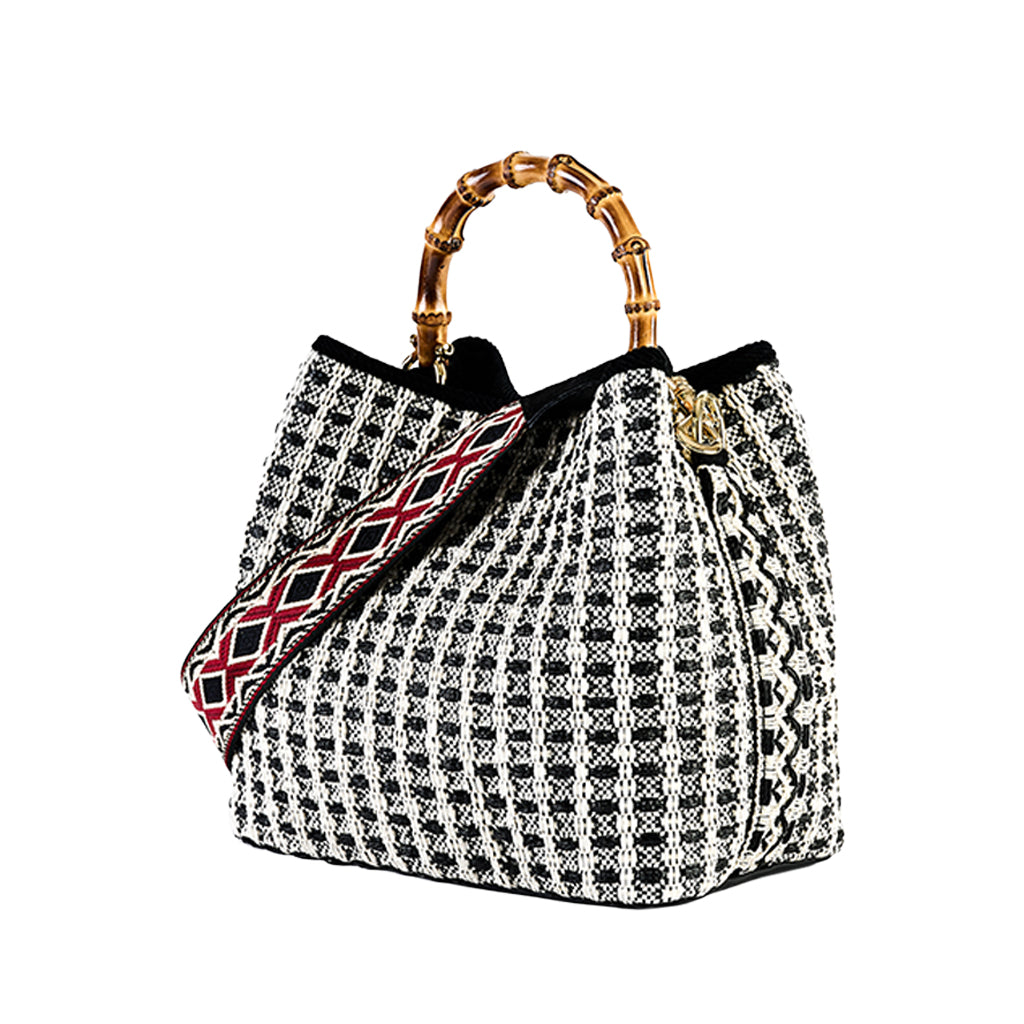 Black and white houndstooth handbag with bamboo handles and red patterned strap