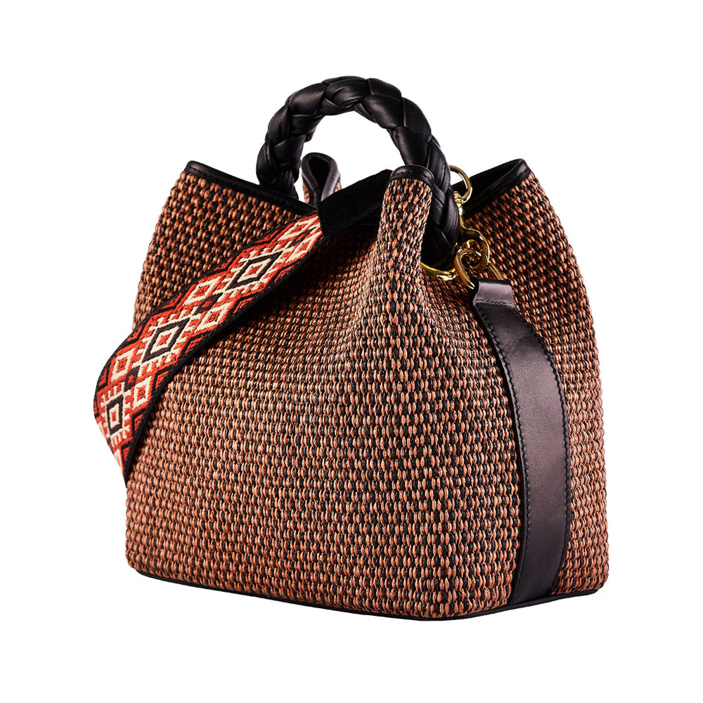 Woven brown handbag with intricate red patterned shoulder strap and braided black handles