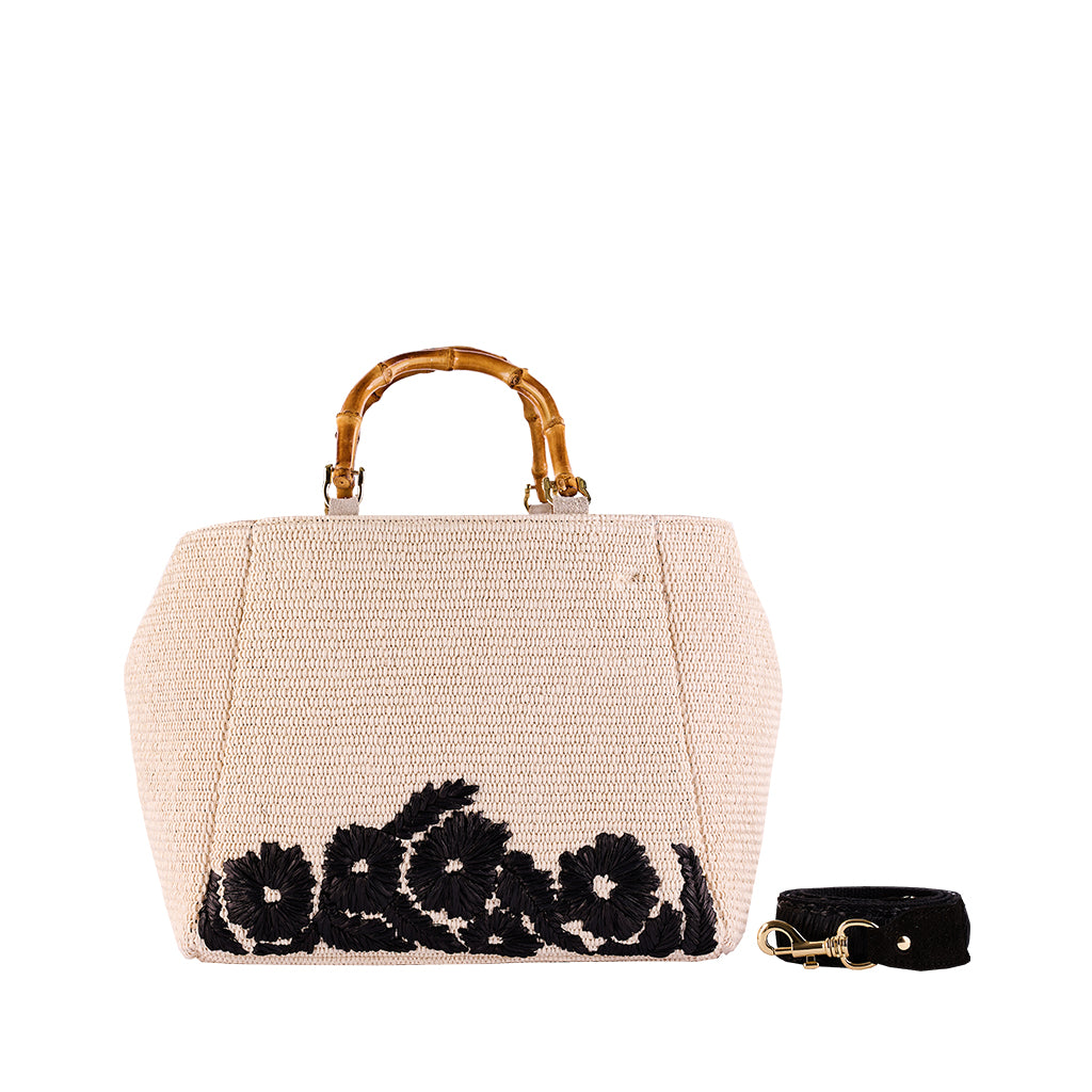 Beige woven handbag with black floral embroidery, bamboo handle, and detachable strap