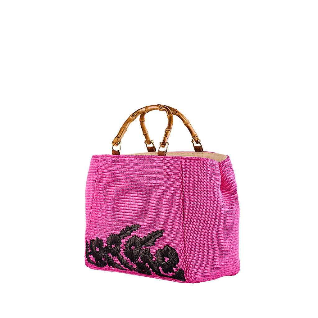 Pink woven handbag with bamboo handles and black floral embroidery