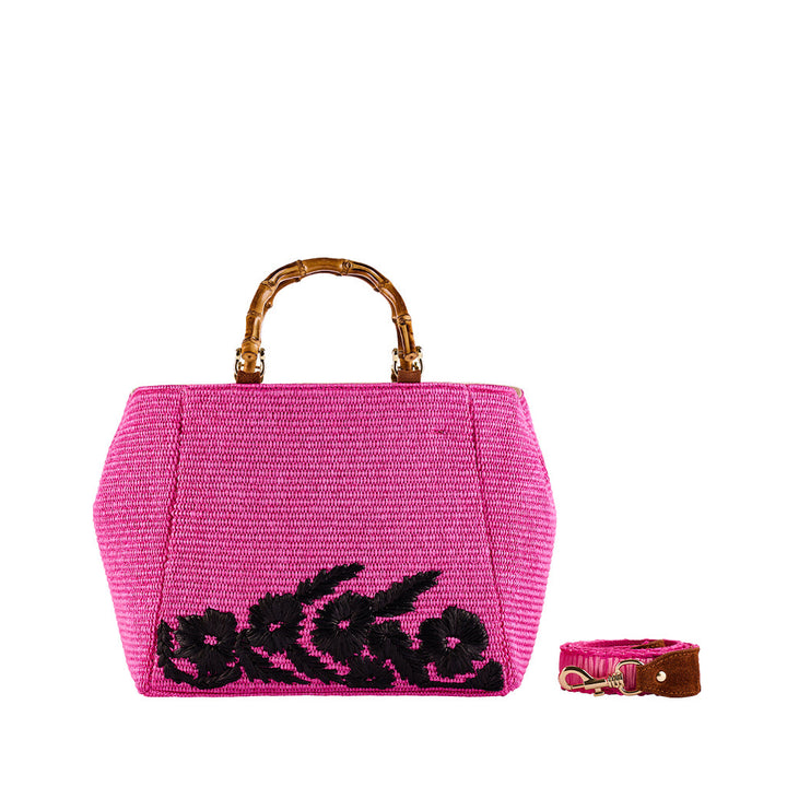 Pink woven handbag with bamboo handle and black floral design