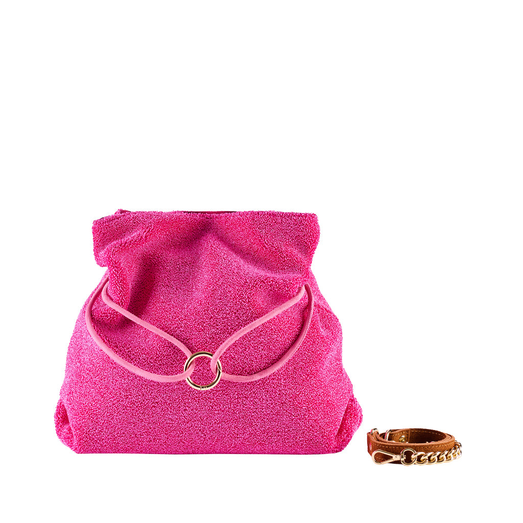 Bright pink textured handbag with gold ring clasp and brown leather bracelet adjacent