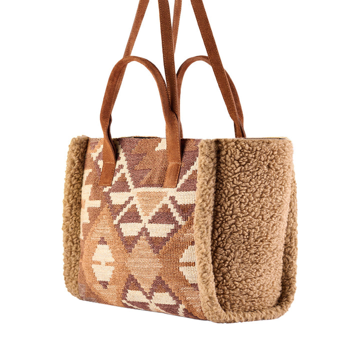 Brown Aztec-patterned tote bag with leather straps and plush trim