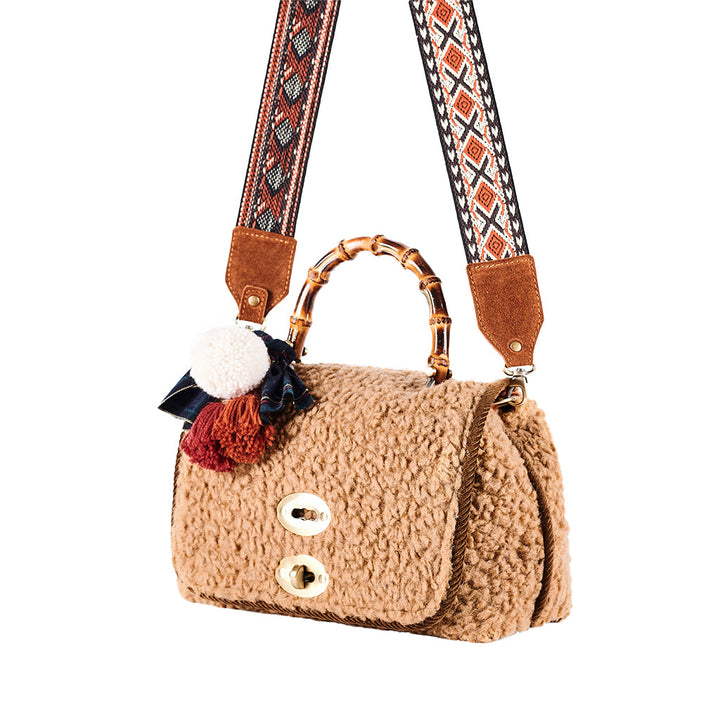 Stylish beige faux shearling handbag with decorative pom-poms and patterned shoulder strap