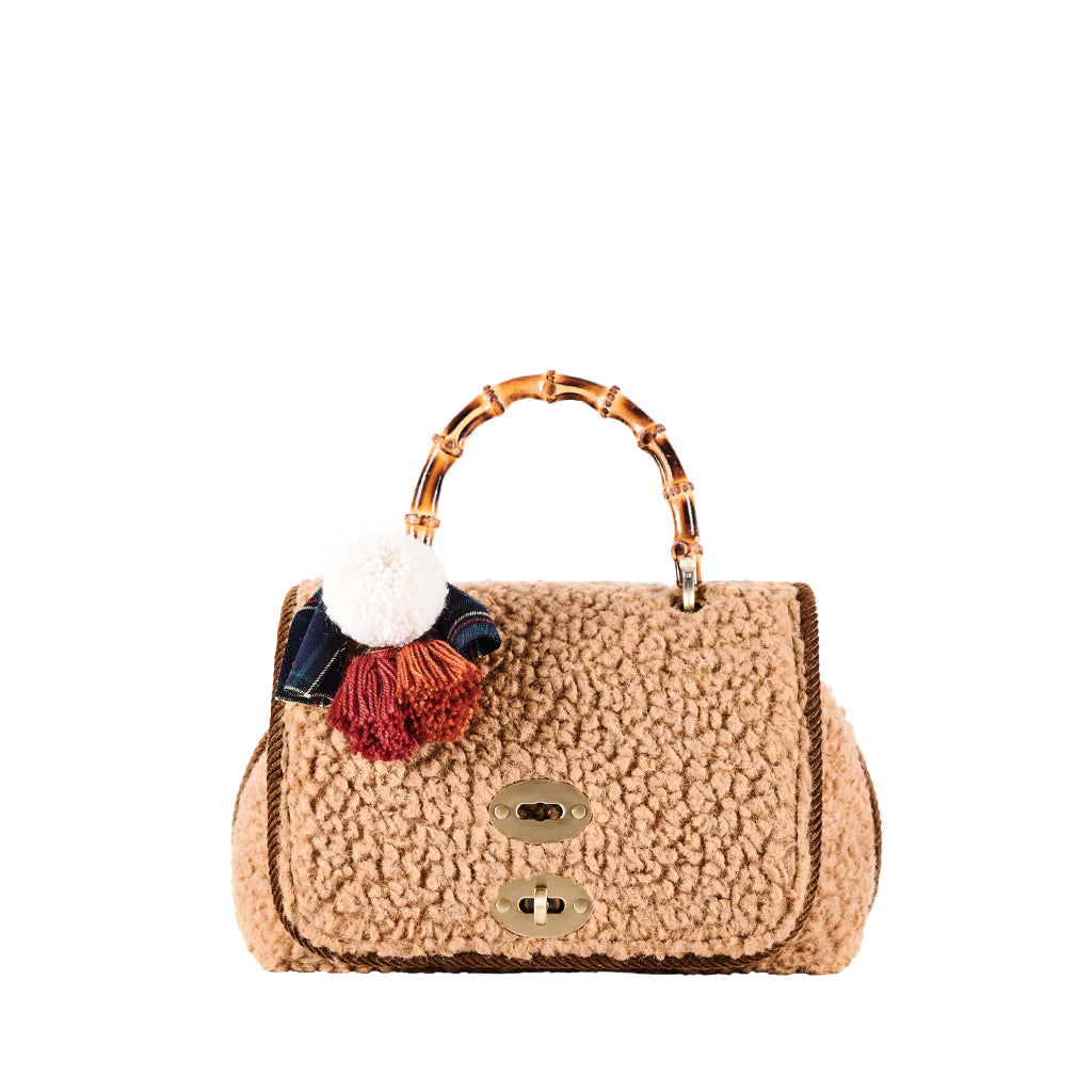 Beige textured handbag with bamboo handle and colorful pom-pom accessory