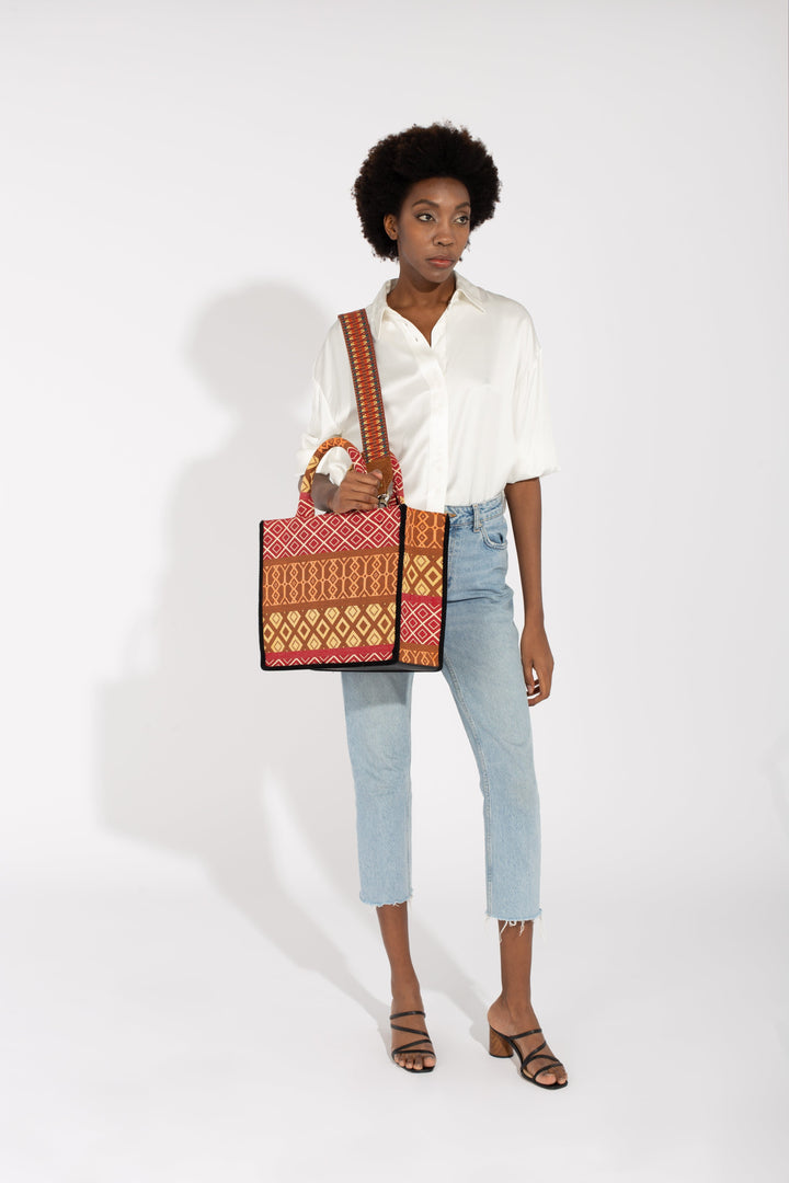 Woman wearing casual outfit and holding a colorful patterned tote bag