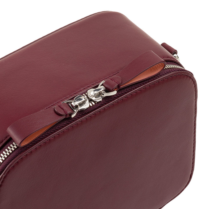 Close-up of a maroon leather handbag with silver zipper details