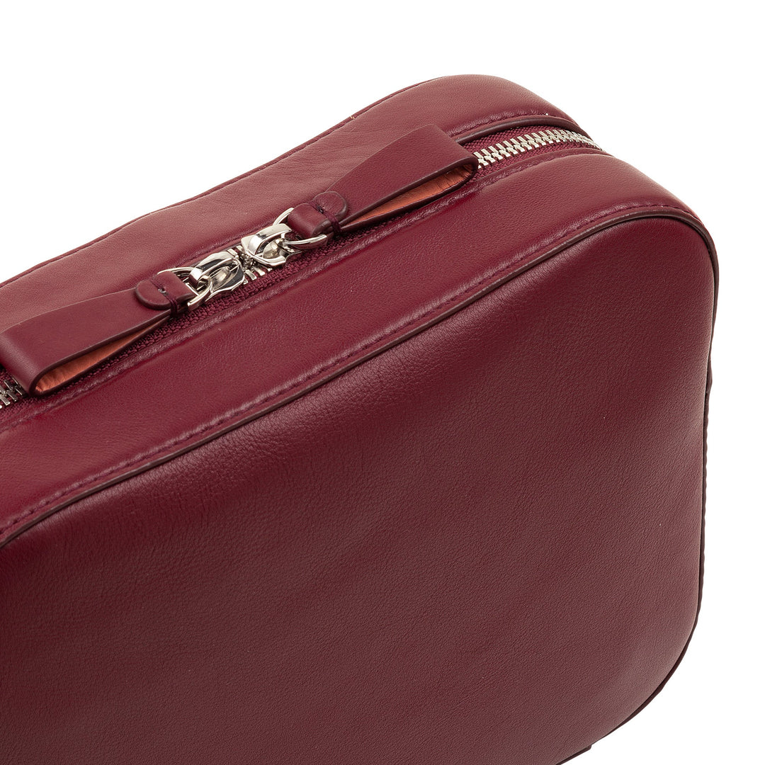 Close-up of a red leather handbag with silver zipper and bow detail