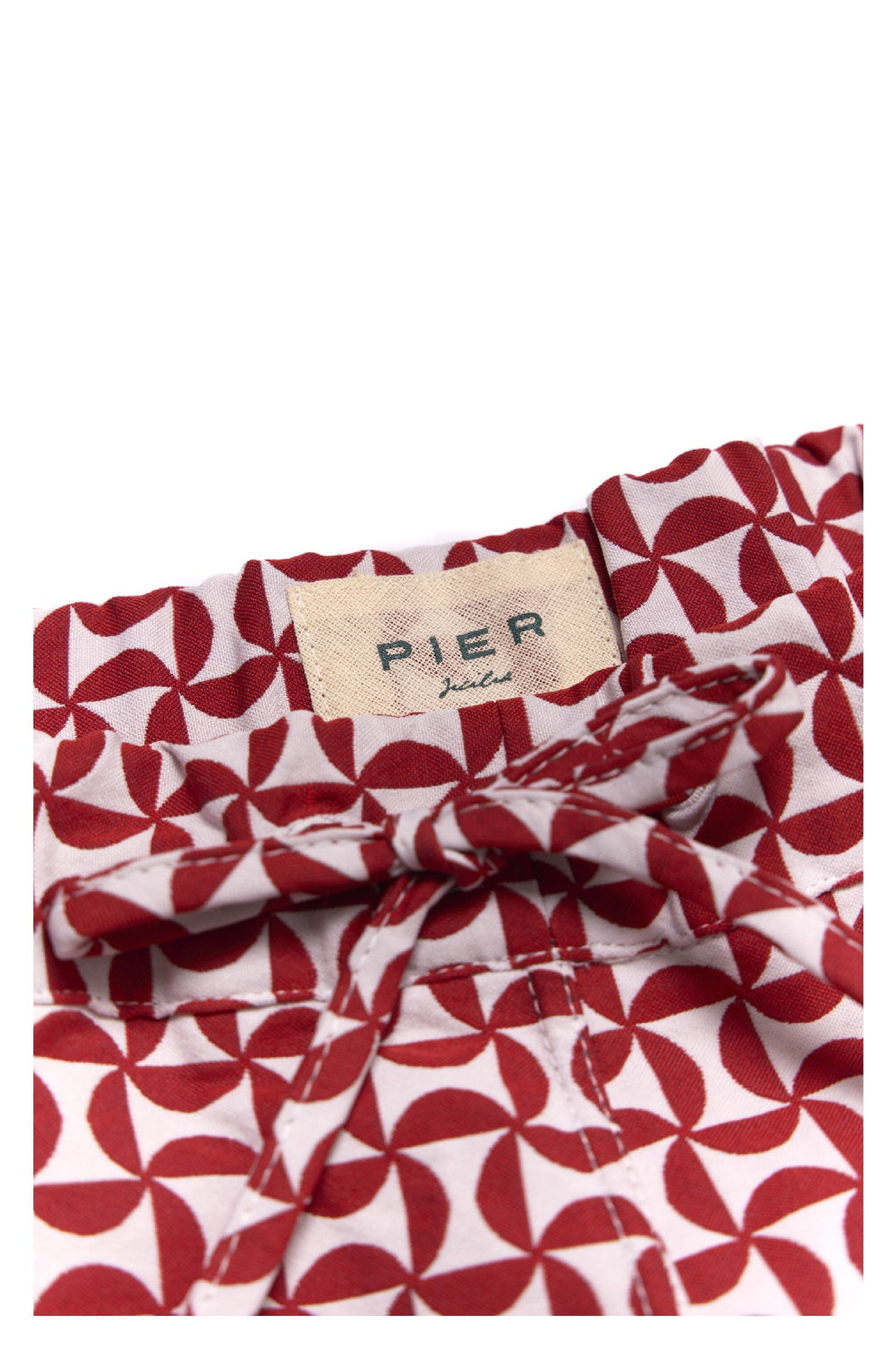 Close-up of red and white geometric patterned Pier swim trunks with label