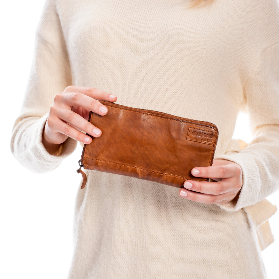 Person holding a brown leather wallet against a light background