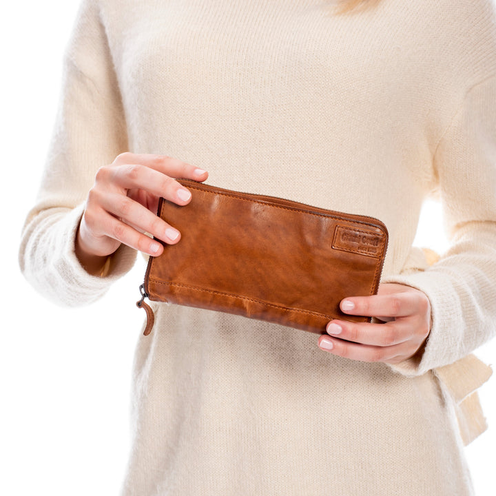 Person holding a brown leather wallet against a light background