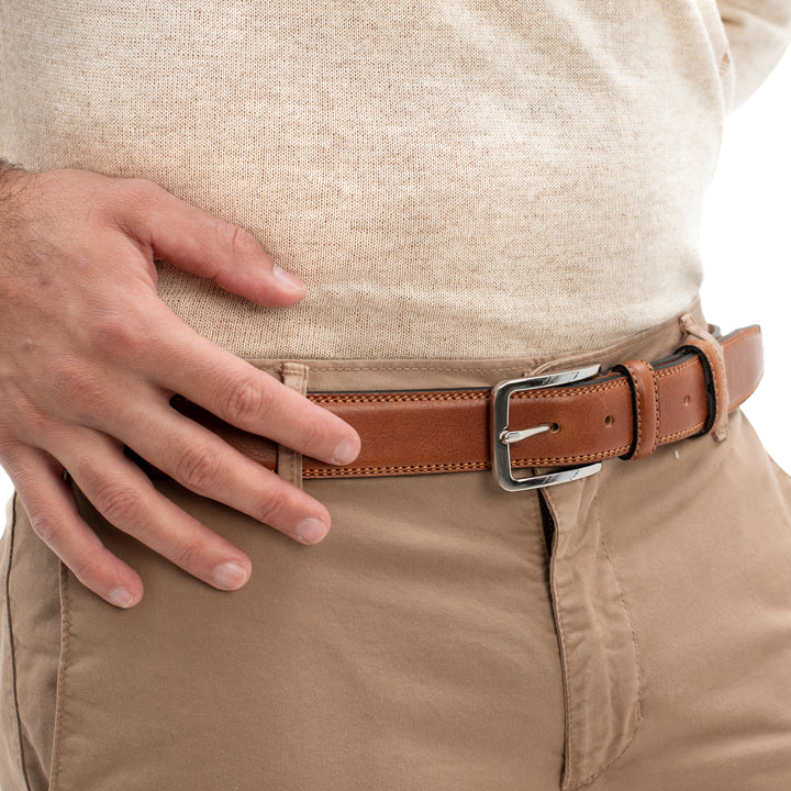 Close-up of a person wearing a beige sweater, brown leather belt, and tan pants