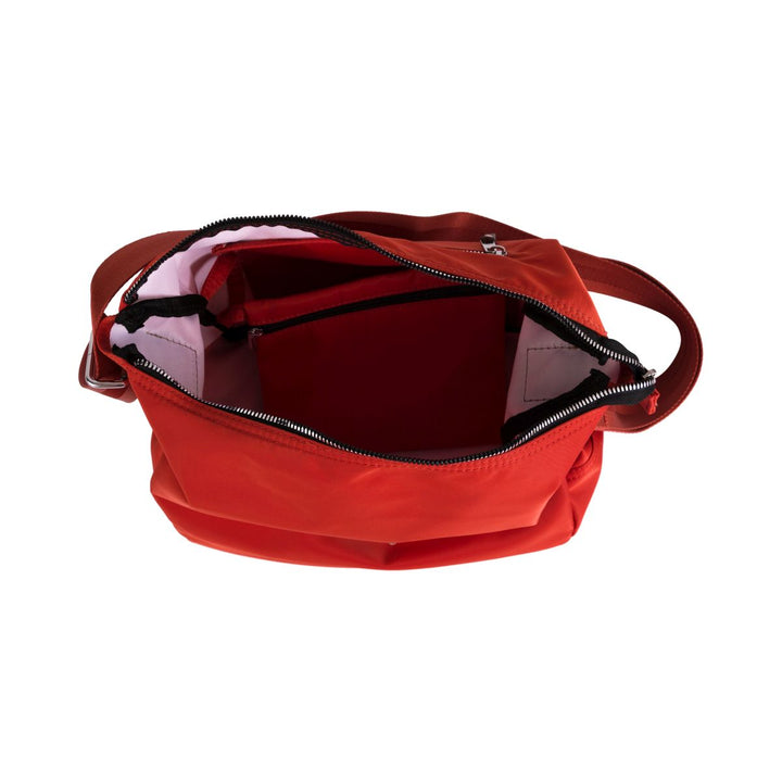 Top view of an open red shoulder bag with compartments and zipper