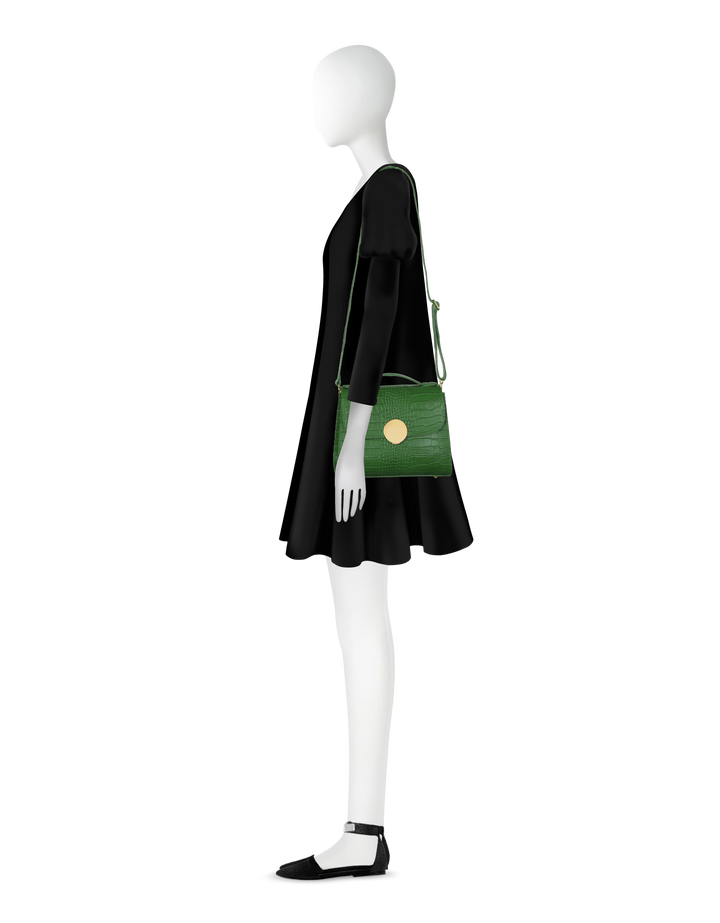 Minimalistic mannequin in black dress holding green shoulder bag