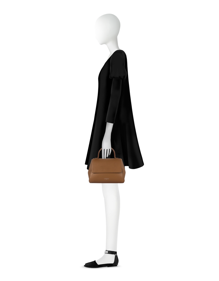 Elegant mannequin in black dress holding brown leather handbag