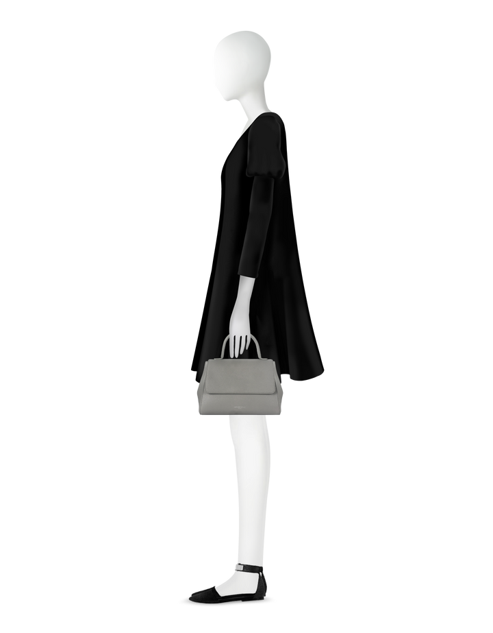 Minimalist mannequin wearing black dress holding gray handbag side view