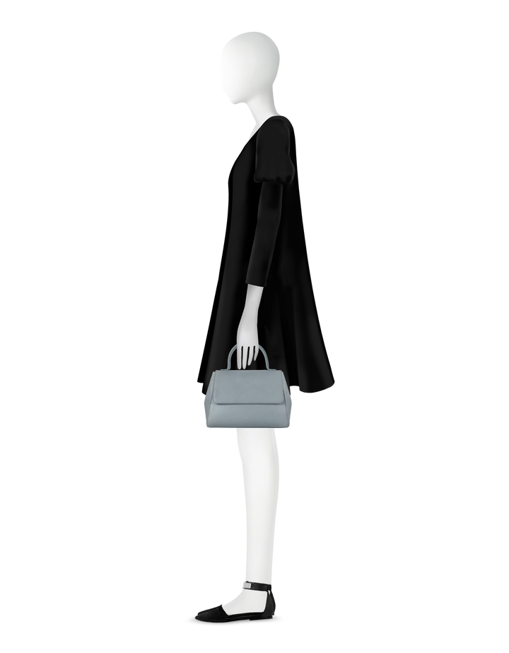 Side view of a mannequin wearing a black dress and holding a light gray handbag