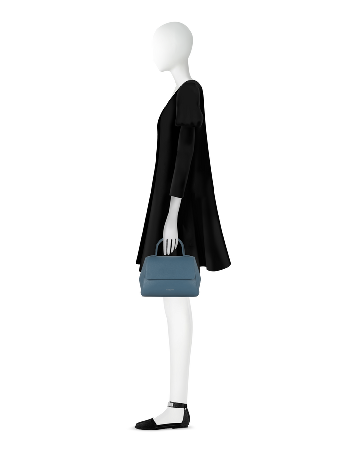 Mannequin in black dress holding blue handbag