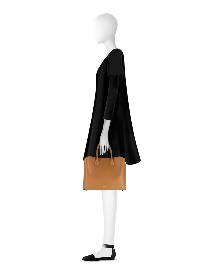 Side profile of a mannequin wearing a black dress, holding a brown leather handbag, and wearing black ankle-strap shoes