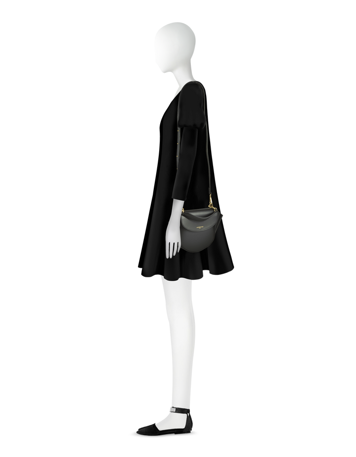 Side view of mannequin dressed in black dress with shoulder bag and flat shoes