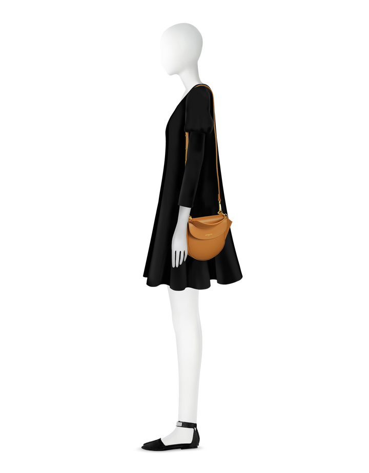 Woman mannequin wearing black dress with tan crossbody bag and black flats, side profile