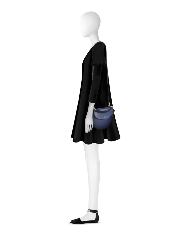 Side view of a mannequin wearing a black dress and holding a blue shoulder bag