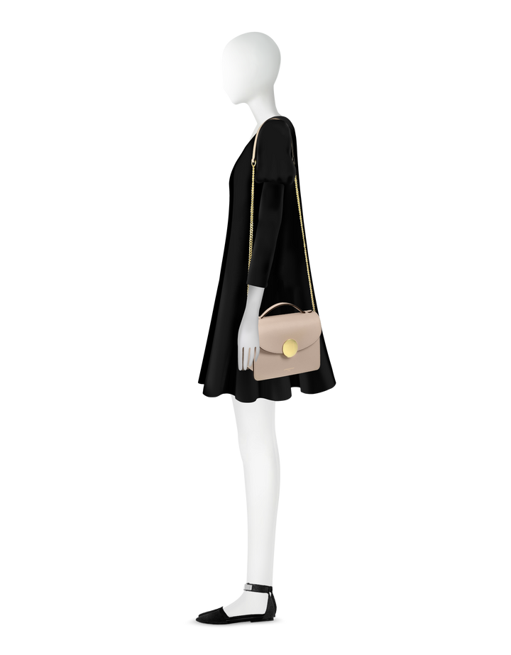 Side profile of a mannequin wearing a black dress with a beige crossbody bag and black shoes