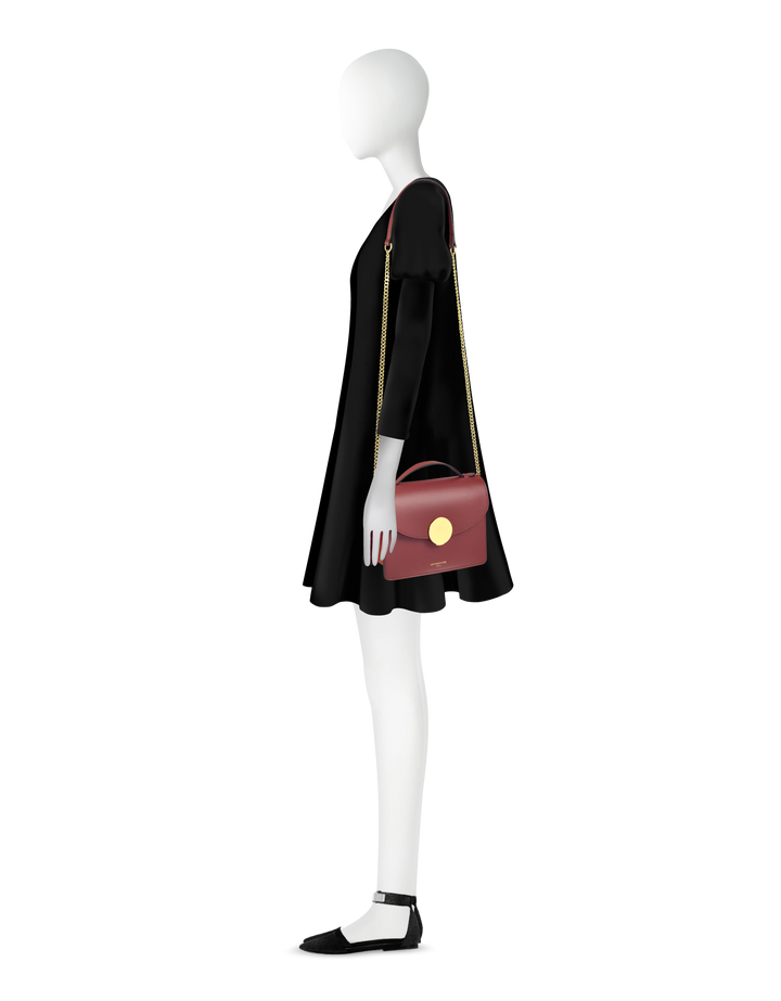 Mannequin in black dress with red handbag and black shoes