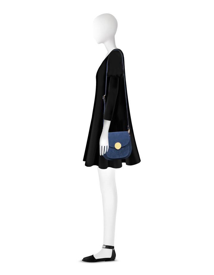 Model wearing a black dress with a blue crossbody bag and black flats