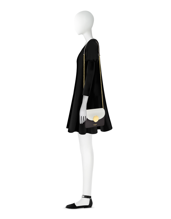 Side view of a mannequin wearing a black dress with a gold chain handbag