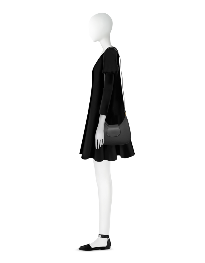 Side view of a mannequin wearing a black dress and black shoulder bag