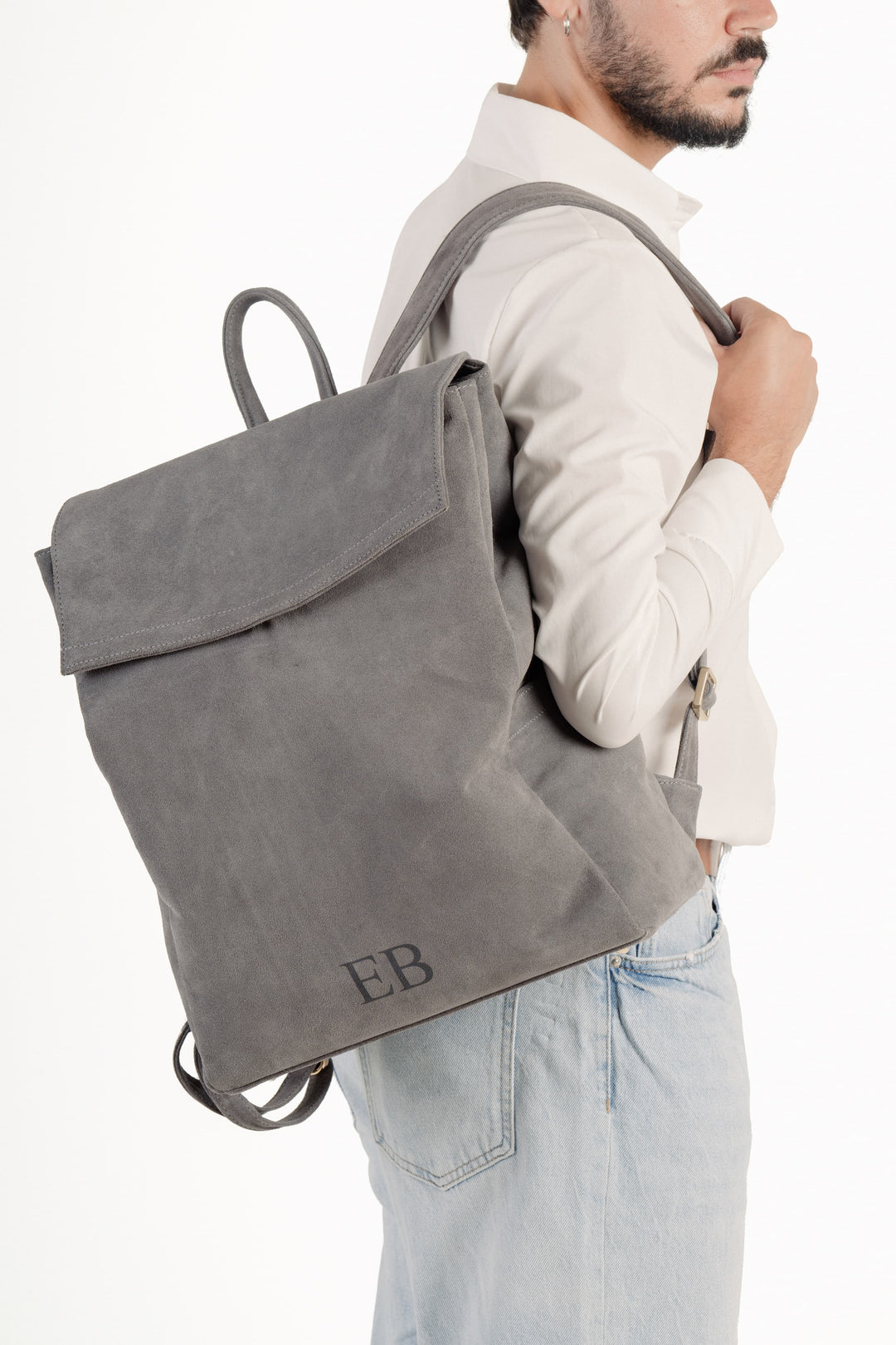 Man wearing a light gray backpack with initials EB embroidered on the front